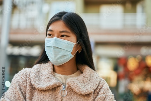 Young asian woman wearing medical mask standing at the city. © Krakenimages.com