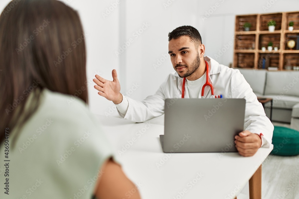 Doctor explain treatment to latin woman using laptop at clinic Doctor explain treatment to latin woman using laptop at clinic