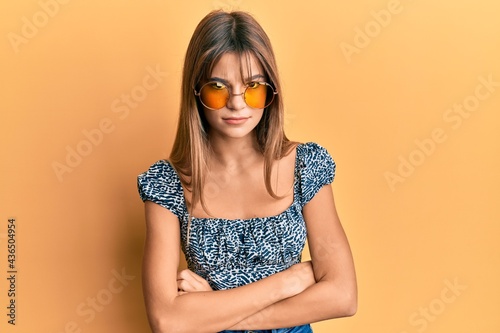 Teenager caucasian girl wearing fashion yellow sunglasses skeptic and nervous, disapproving expression on face with crossed arms. negative person.