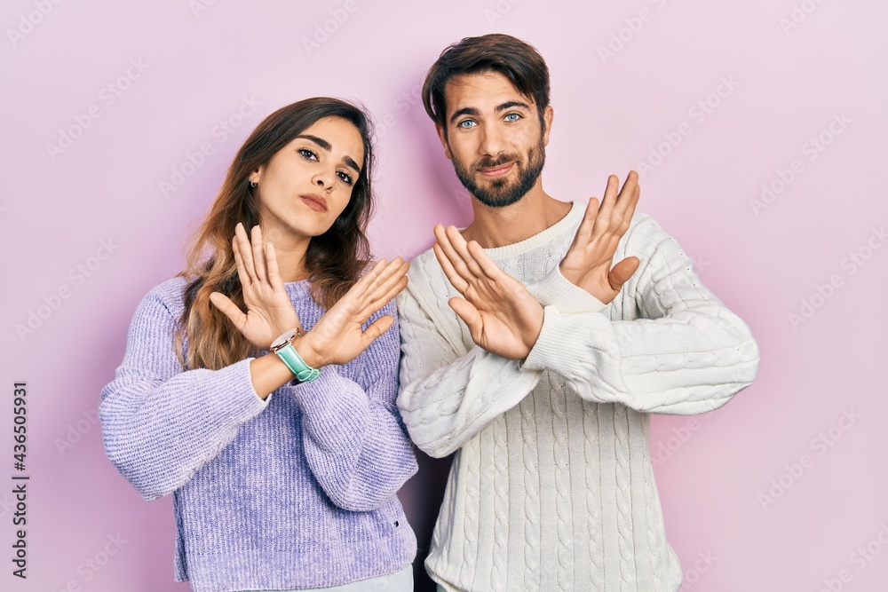 Young hispanic couple wearing casual clothes rejection expression crossing arms doing negative sign, angry face Young hispanic couple wearing casual clothes rejection expression crossing arms doing negative sign, angry face
