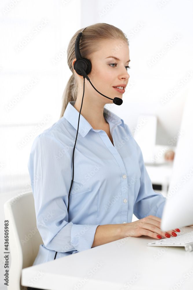 Blond woman working in sunny call center. Group of diverse people working as customer service occupation. Business concept Blond woman working in sunny call center. Group of diverse people working as customer service occupation. Business concept