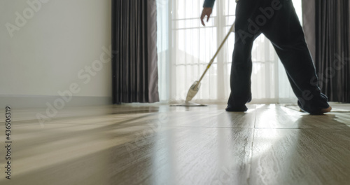 Asian boy doing house chore by cleaning the floor.