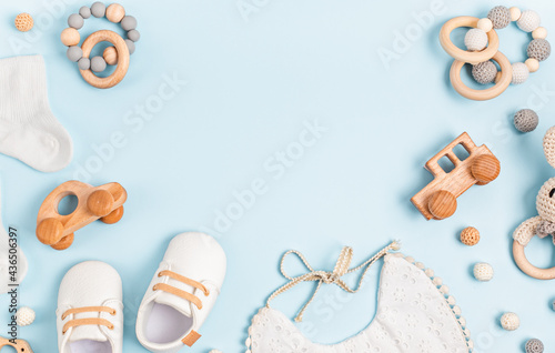 Baby shoes, bib and teether on pastel background. Organic newborn accessories
