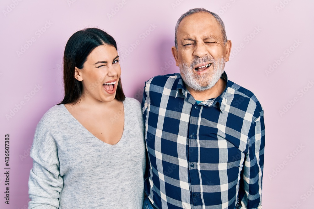 Hispanic father and daughter wearing casual clothes winking looking at the camera with sexy expression, cheerful and happy face. Hispanic father and daughter wearing casual clothes winking looking at the camera with sexy expression, cheerful and happy face.