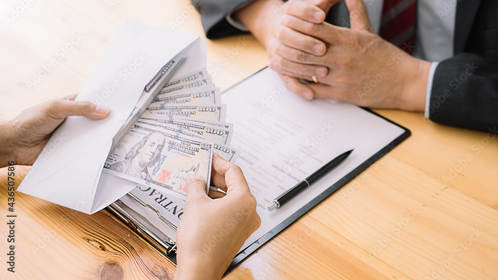 Businessman giving money while making deal to agreement a real estate contract and financial corporate.Bribery and corruption concept Businessman giving money while making deal to agreement a real estate contract and financial corporate.Bribery and corruption concept
