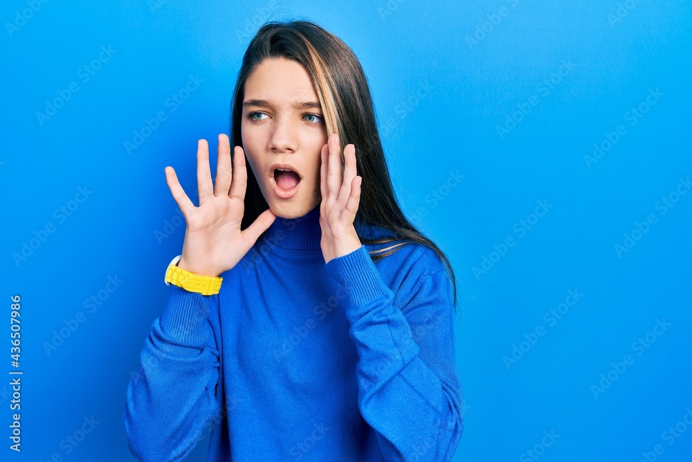 Young brunette girl wearing turtleneck sweater shouting angry out loud with hands over mouth Young brunette girl wearing turtleneck sweater shouting angry out loud with hands over mouth