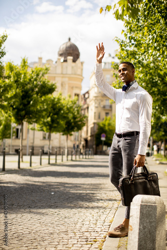 Young African American businessman waitng a taxi on a street photo