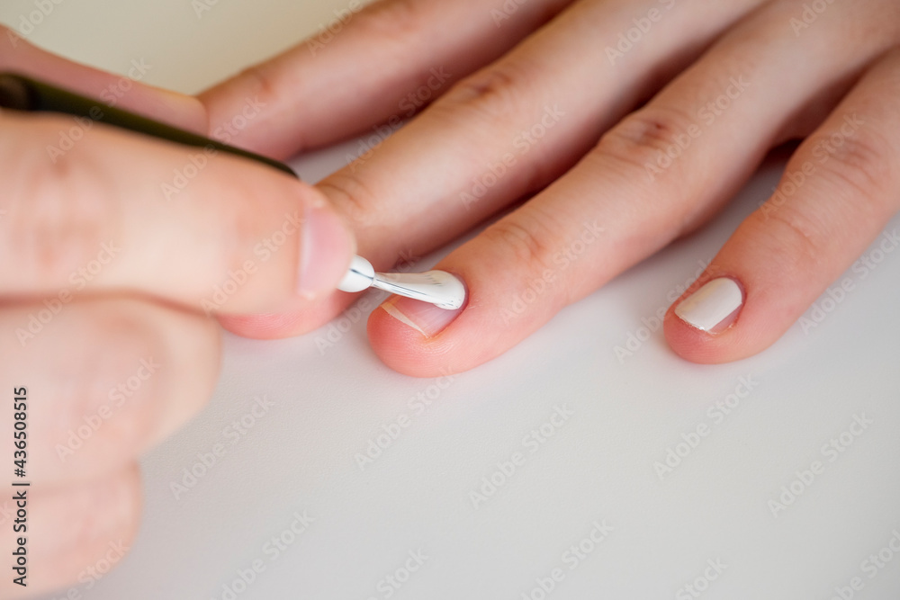 applying white nail polish to the nail. Manicure and nail care concept applying white nail polish to the nail. Manicure and nail care concept