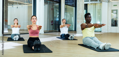 Young sporty men and women stretching attending pilates class