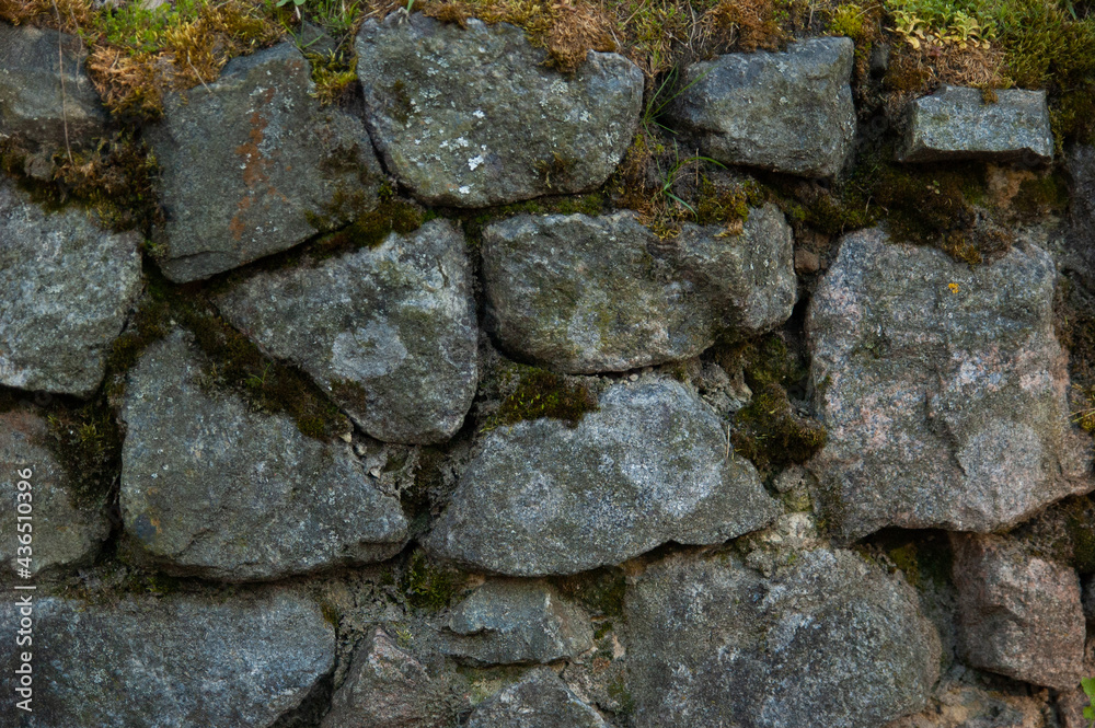a wall of rough granite stones, with moss in the cracks