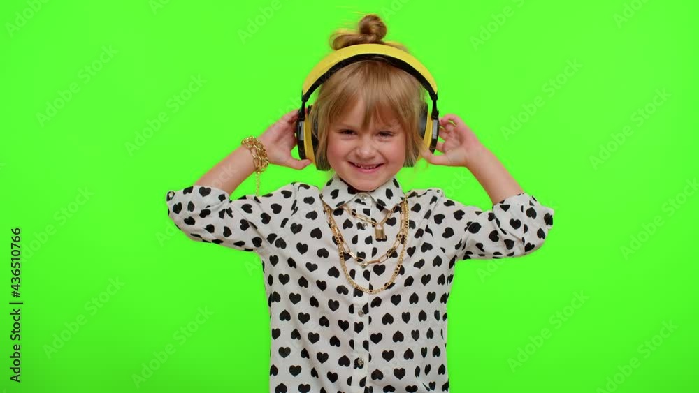 Attractive blonde child kid 5-6 years old listening music via headphones, dancing disco fooling around having fun expressive gesticulating hands. Teenager children girl on chroma key green background Attractive blonde child kid 5-6 years old listening music via headphones, dancing disco fooling around having fun expressive gesticulating hands. Teenager children girl on chroma key green background
