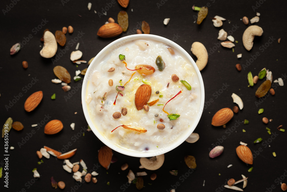 Close-up of Creamy rice Kheer(khir) Garnished with saffron and dry fruits. Indian delicious dessert. Served in white ceramic bowl. Top View on black background. Close-up of Creamy rice Kheer(khir) Garnished with saffron and dry fruits. Indian delicious dessert. Served in white ceramic bowl. Top View on black background.