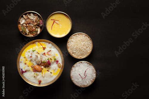 Close-up of Creamy rice Kheer(khir) Garnished with saffron and dry fruits for pooja (spiritually celebration). Indian delicious dessert. Served in a ceramic black bowl. Top View on black background.