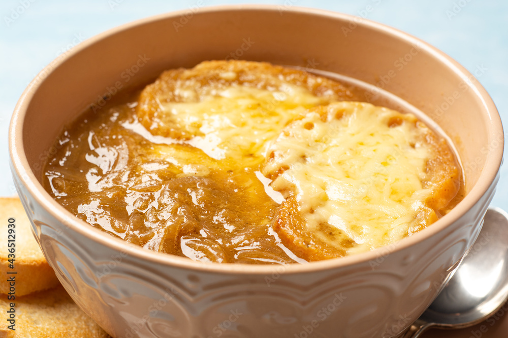 Traditional french onion soup with baguette and cheese in bowl on concrete background Traditional french onion soup with baguette and cheese in bowl on concrete background