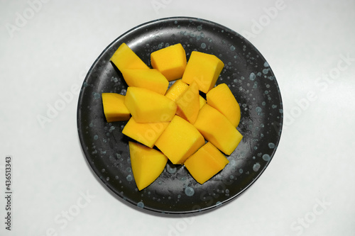 Ripe mangos in a black ceramic dish. photo