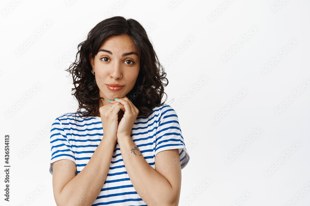 Portrait of lovely brunette woman gazing at camera, looking lovely and romantic, admiring beautiful scene, standing in t-shirt against white background Portrait of lovely brunette woman gazing at camera, looking lovely and romantic, admiring beautiful scene, standing in t-shirt against white background