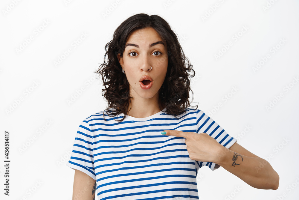 Portrait of surprised brunette girl pointing at herself, gasping amazed, being chosen, winning something, look with disbelief and excitement, standing over white background Portrait of surprised brunette girl pointing at herself, gasping amazed, being chosen, winning something, look with disbelief and excitement, standing over white background
