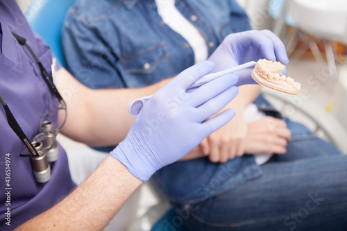 Fototapeta Naklejka Na Ścianę i Meble -  Unrecognizable dentist showing dental mold to the patient