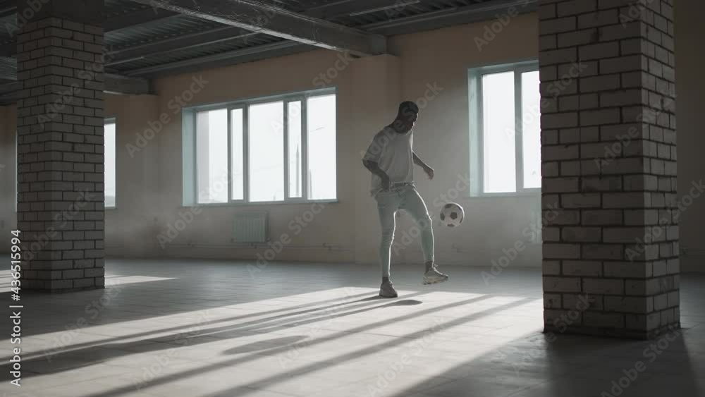 Black man football soccer player practicing tricks, kicks and moves with ball inside empty covered parking garage. African boy freestyle training in Urban city . Slow motion RAW graded footage Black man football soccer player practicing tricks, kicks and moves with ball inside empty covered parking garage. African boy freestyle training in Urban city . Slow motion RAW graded footage