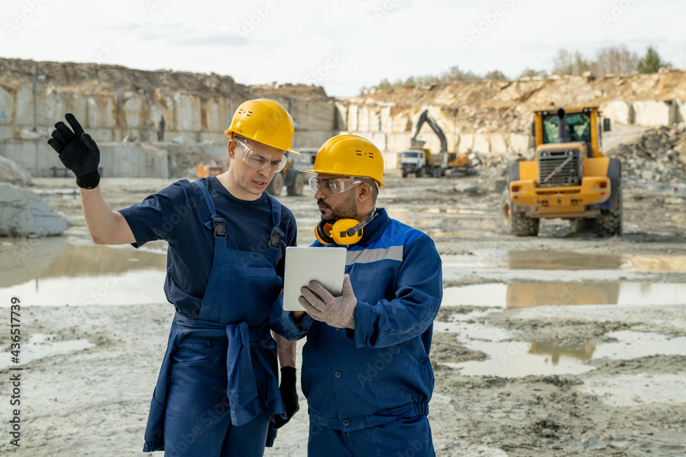 Contemporary builders discussing sketch in tablet during work