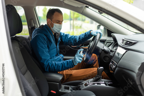 Covid-19 concept. Man drives in car, wears medical gloves, protects himself from bacteria and virus, holds car steering wheel. Coronavirus protection. Transport, quarantine and corona disease. © Angelov
