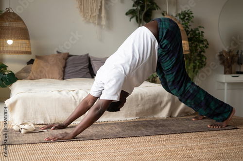 Young african man working out, standing in yoga downward facing dog pose, adho mukha svanasana photo