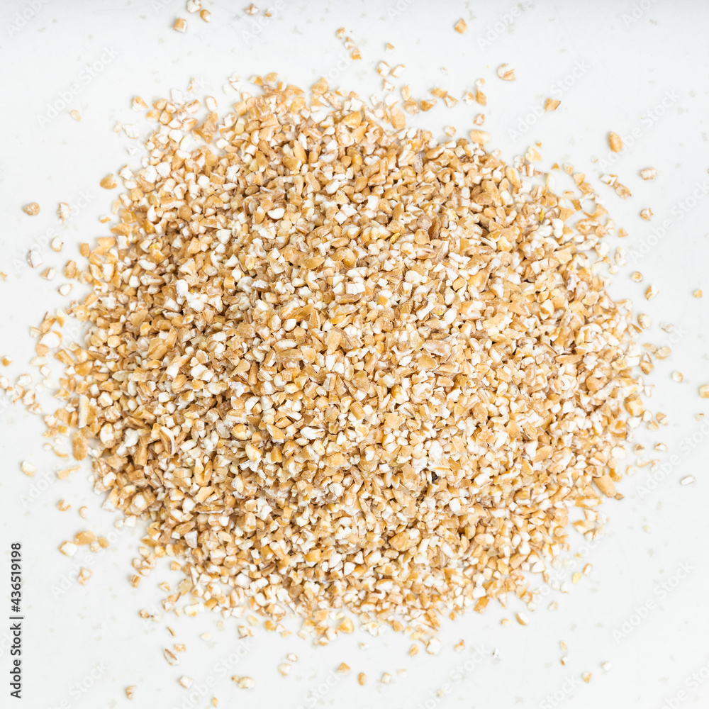 pile of partly hulled wheat groats closeup on gray pile of partly hulled wheat groats closeup on gray