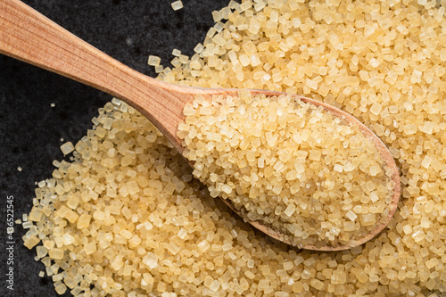 spoon with demerara brown cane sugar on black photo