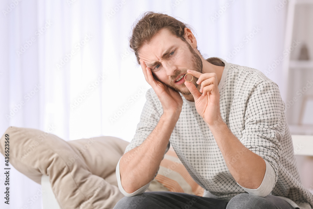 Upset young man with wedding ring after quarrel at home Upset young man with wedding ring after quarrel at home