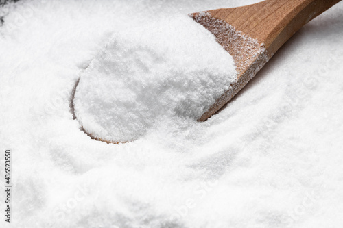 Photos wooden spoon with dextrose sugar close up on pile