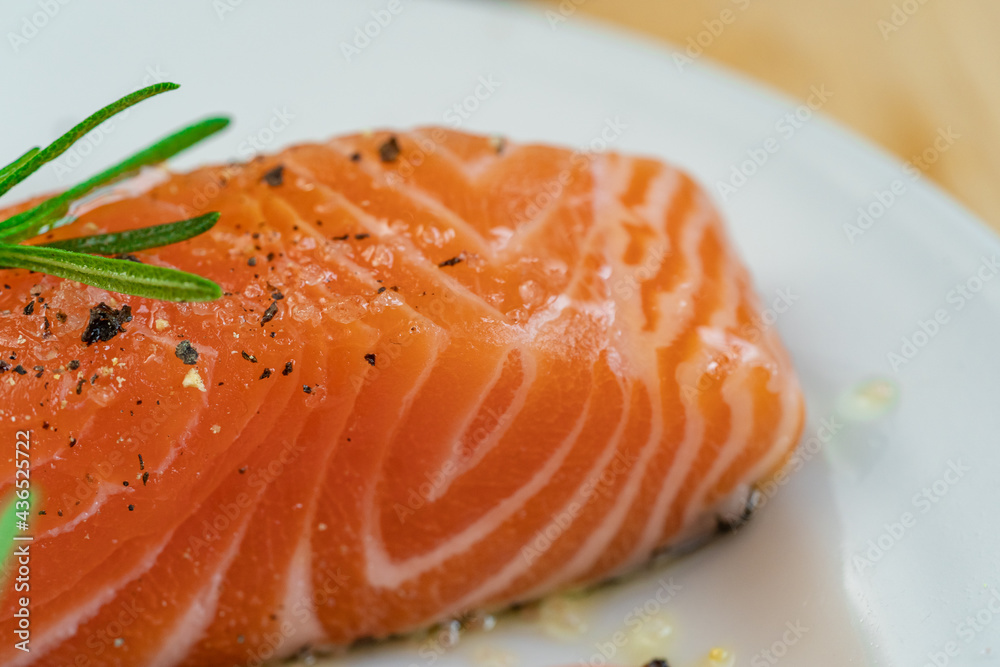 Salmon steak a piece of fresh home cooking with rosemary, olive oil, black pepper and himalayan salt on a white plate. Focus select and blur close up and Macro photography. Salmon steak a piece of fresh home cooking with rosemary, olive oil, black pepper and himalayan salt on a white plate. Focus select and blur close up and Macro photography.