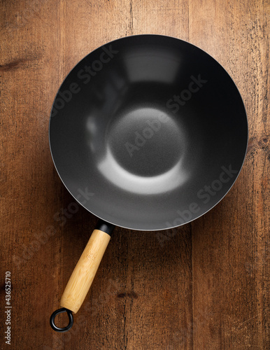 Traditional Asian Wok pan for stir fry cooking with wooden handle on rustic table