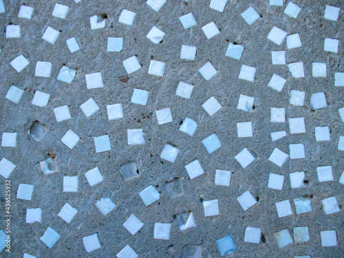 Background from a gray wall with blue smalt cubes. The texture is uneven. Several dice have dropped out. The drawing is chaotic. 
