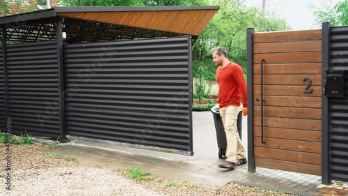 The homeowner remotely opens the gate to roll out the dumpster.