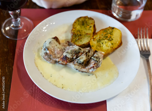 Popular dish of pork with Roquefort cheese sauce with baked potatoes and herbs