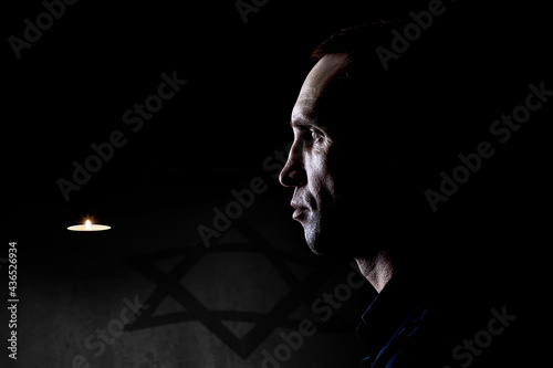 A man near a burning candle on the background of the flag of Israel. Holocaust Memorial Day. photo