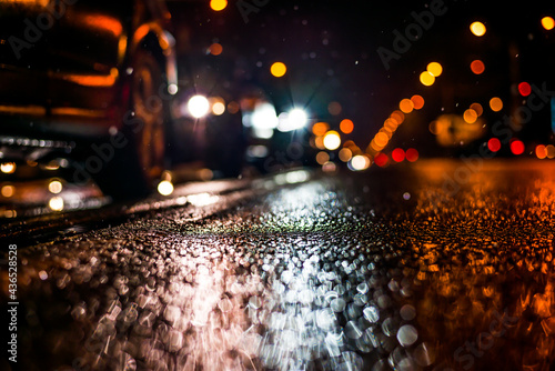 Rainy night in the big city, stream of cars traveling along the avenue. View from the level of the double solid line