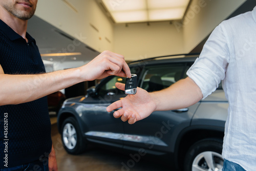 The seller passes the keys to a new car to a young family. Buying a new car