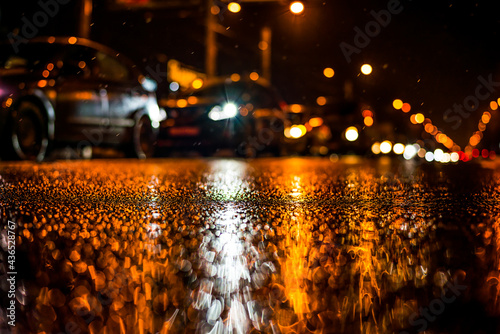 Rainy night in the big city  dense traffic at a busy avenue in the light of lanterns. View from the level of asphalt
