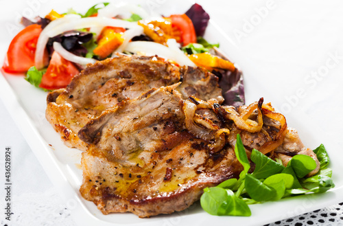 Delicious fried pork chops with salad of fried orange, vegetables and onion