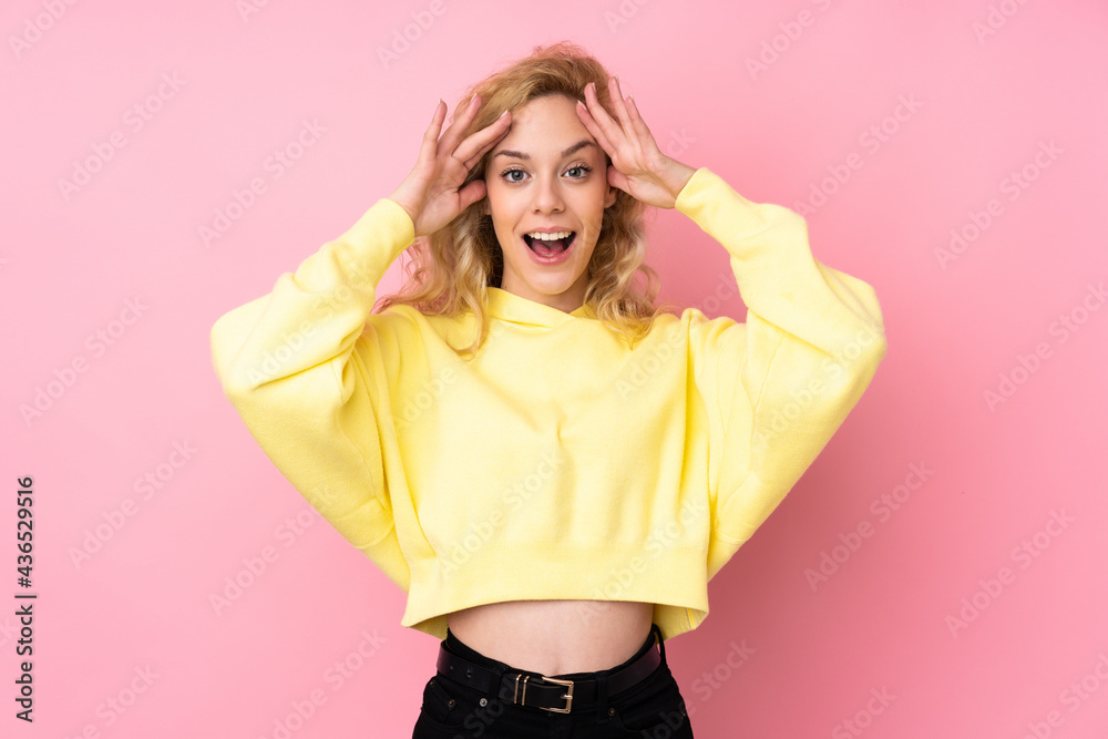 Young blonde woman wearing a sweatshirt isolated on pink background with surprise expression