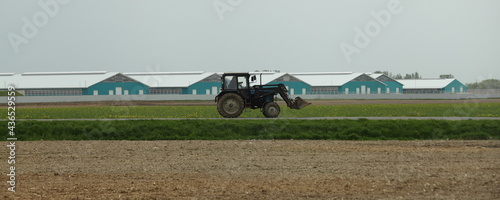 One wheeled Belarus tractor in the brown green field on modern countryfarm background at spring day, rural life rustic landscape photo