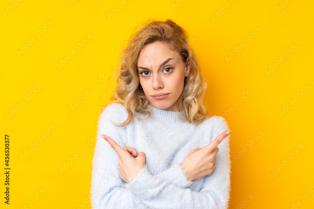 Young blonde woman isolated on yellow background pointing to the laterals having doubts Young blonde woman isolated on yellow background pointing to the laterals having doubts