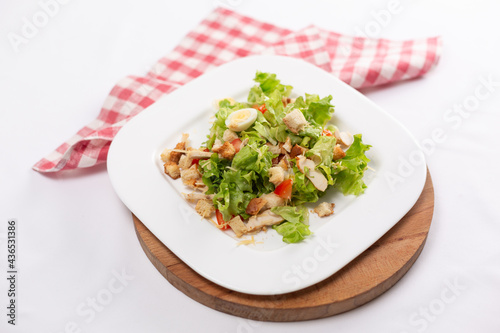 Caesar salad with chicken and eggs on a white plate