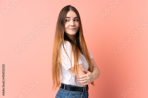 Young caucasian woman isolated on pink background with arms crossed and happy