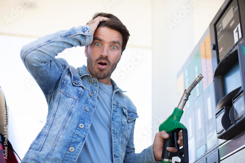 Fototapeta emotional businessman counting money with gasoline refueling car