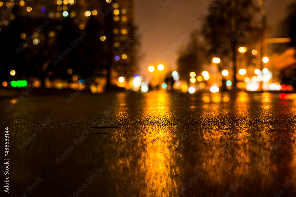 Rainy night in the big city, alley in the city park with walking people. View from the level of asphalt