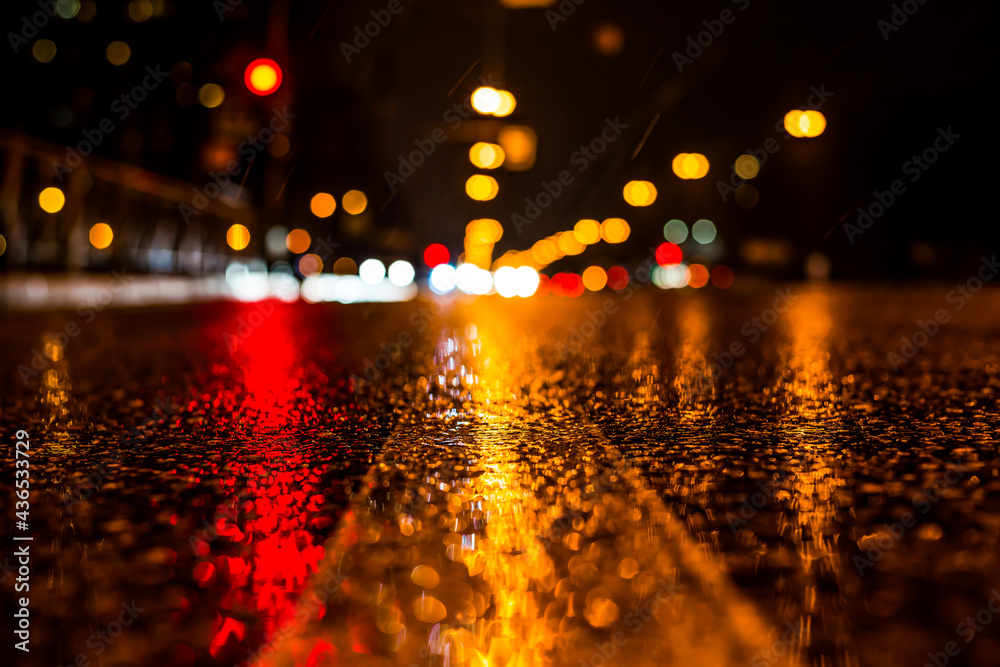 Rainy night in the big city, the glowing lights of approaching cars. View of the level of the dividing line