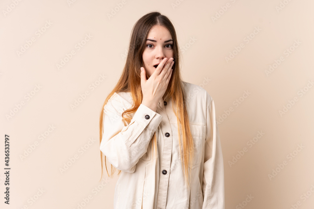 Young caucasian woman isolated on beige background happy and smiling covering mouth with hand Young caucasian woman isolated on beige background happy and smiling covering mouth with hand
