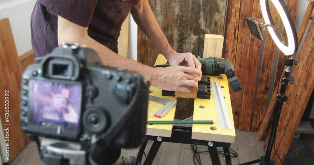 DIY woodworking vlogging, man draw cutting and drilling marks at wood block, using clock mechanism, making wood clock, filming using smartphone with ring light and dslr